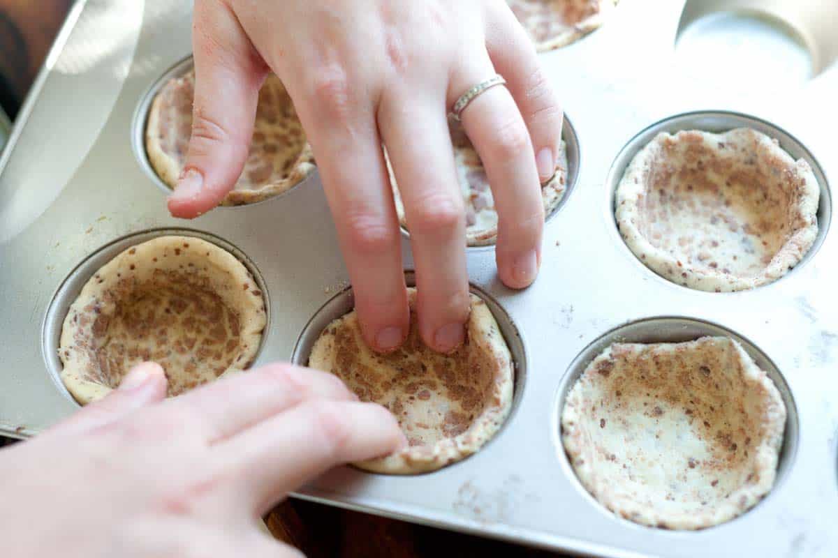 How to Make Apple Pie Cupcakes: Pressing the cinnamon roll crust into cupcake tin