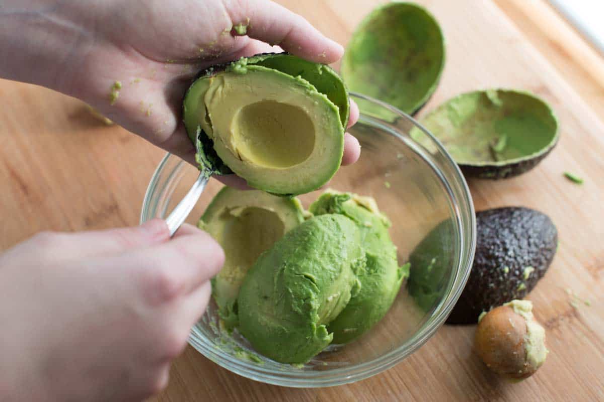 Removing the pit and scooping ripe avocado for guacamole recipe