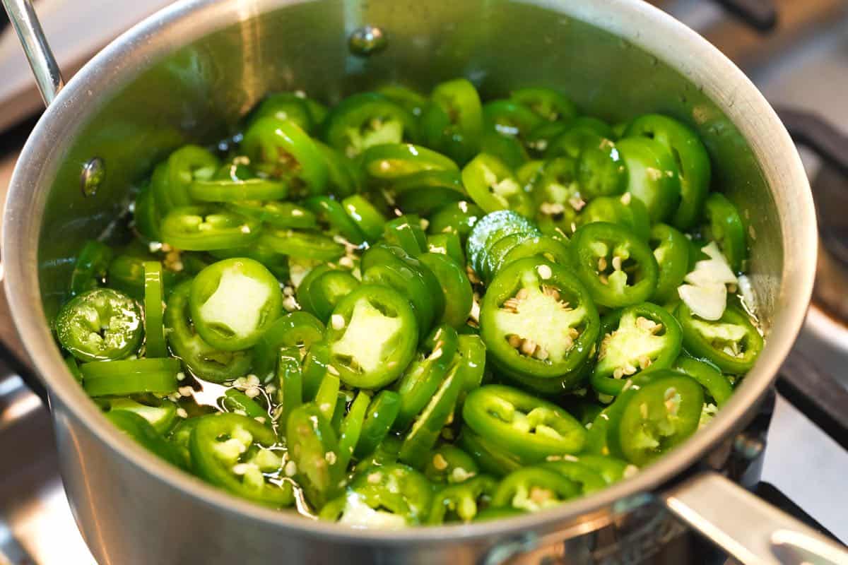 Making our cowboy candy recipe by cooking jalapeños and garlic in a vinegar sugar syrup