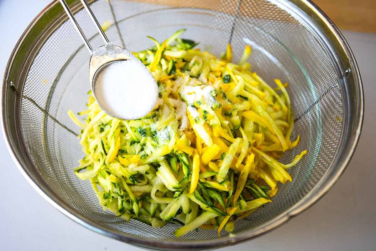Tossing shredded zucchini with sugar for the best zucchini bread