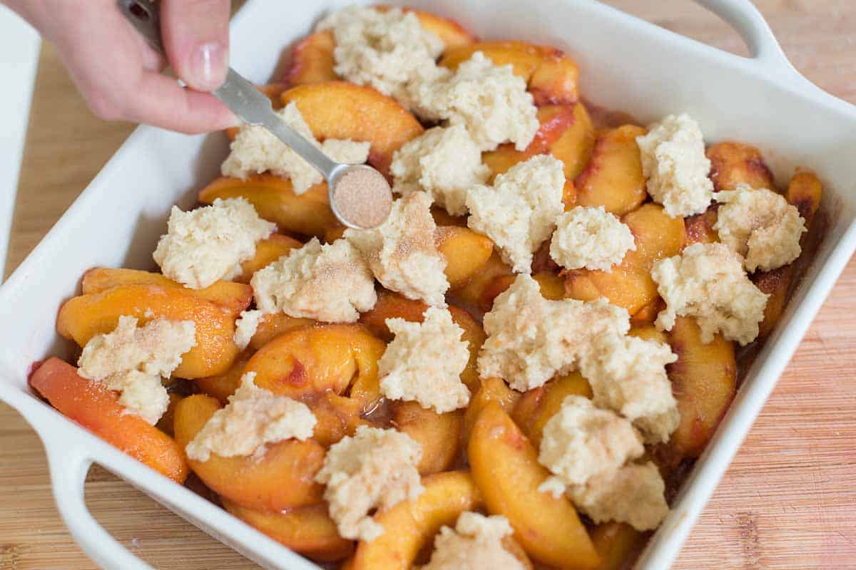 How to Make Peach Cobbler - sprinkling cinnamon sugar over the topping