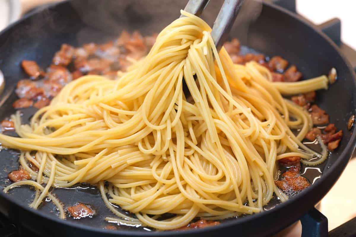 How to Make Pasta Carbonara: Tossing spaghetti with rendered fat.